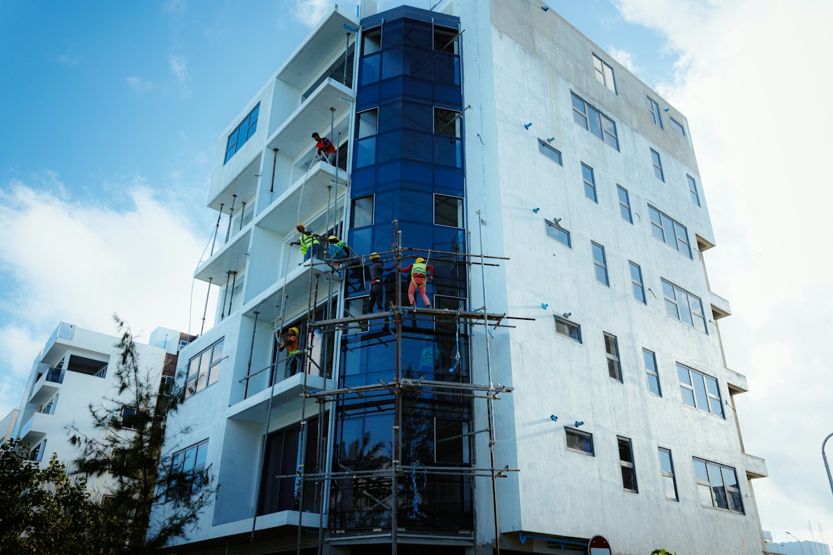 Workers installing a glazed façade beside unfinished building interfaces