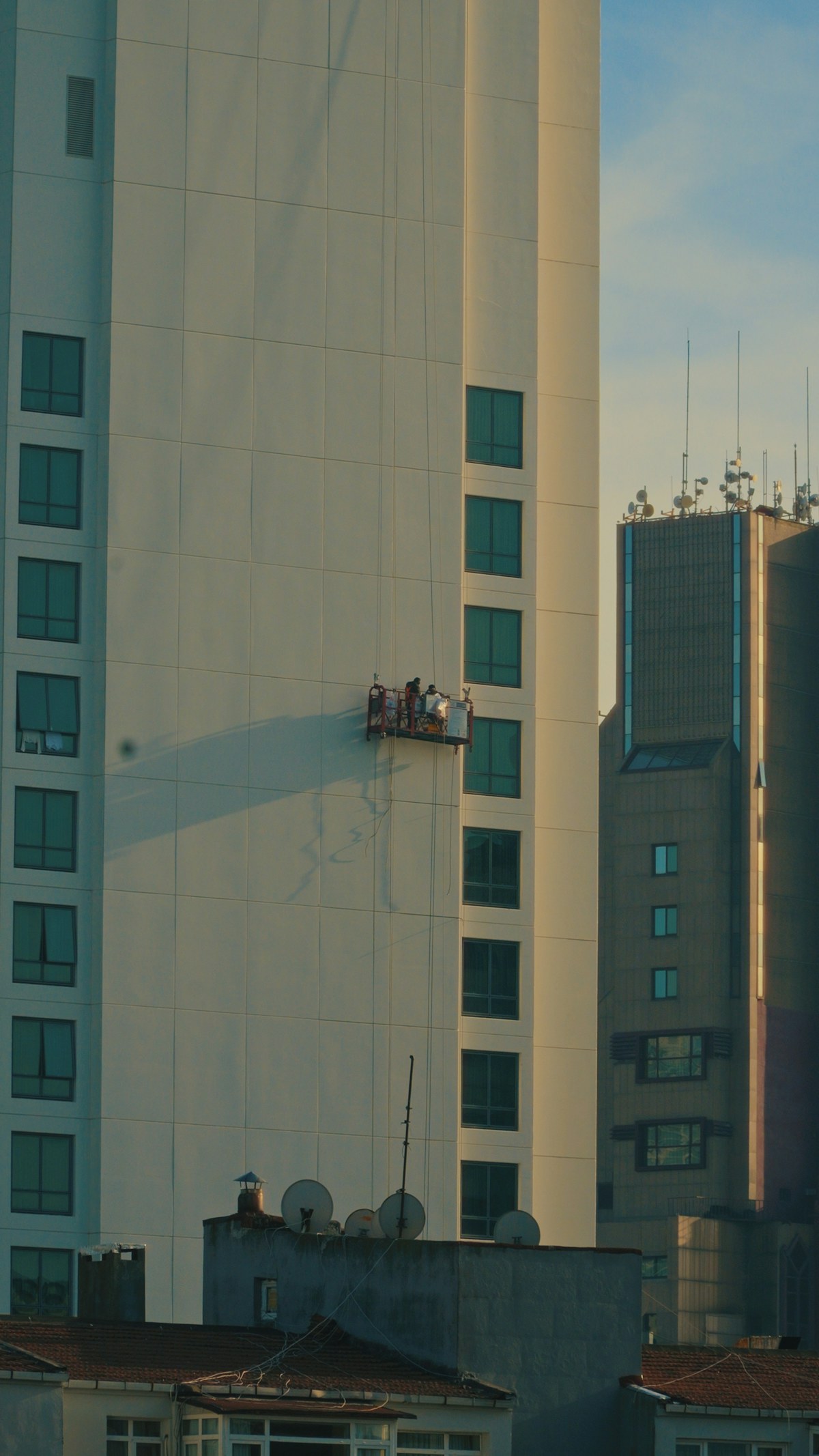 Workers on a suspended platform maintaining the exterior of an existing high-rise building